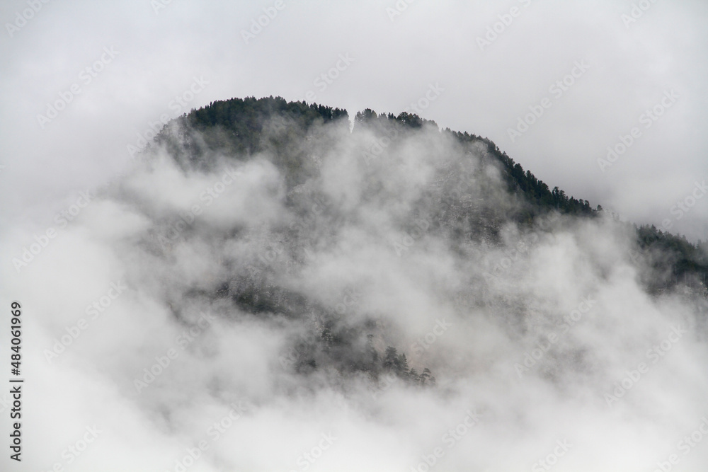 Alpine mountain covered in thick white fog