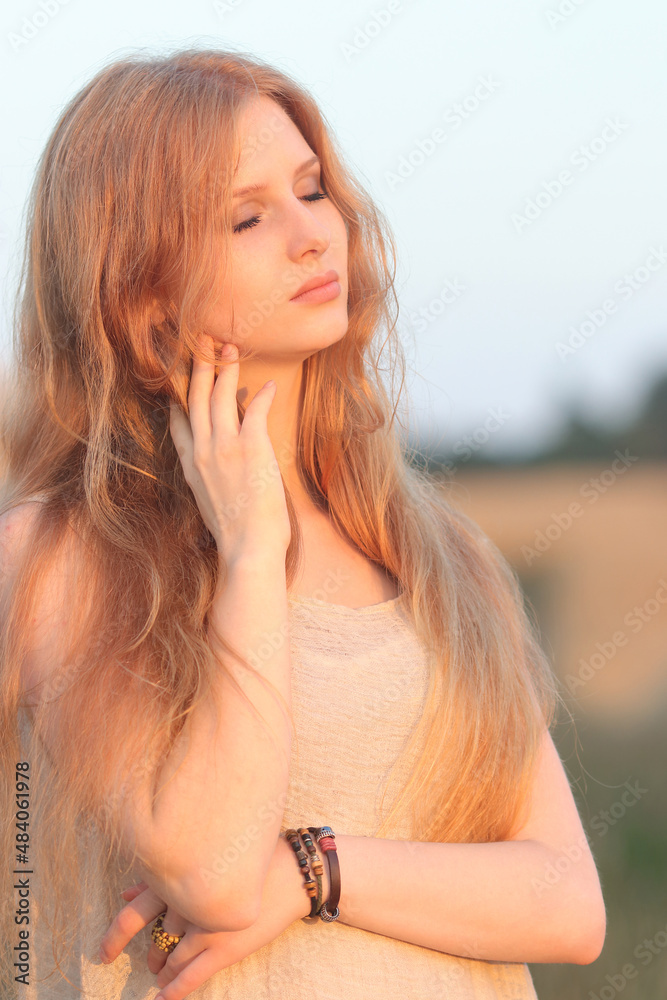 Beautiful Glamour Woman. Young pretty Woman with red hair at the field of wheat. Beauty Girl Outdoors enjoying Nature. Model girl with long healthy hair. Holidays, Travel, Summer, Trip, Lifestyle