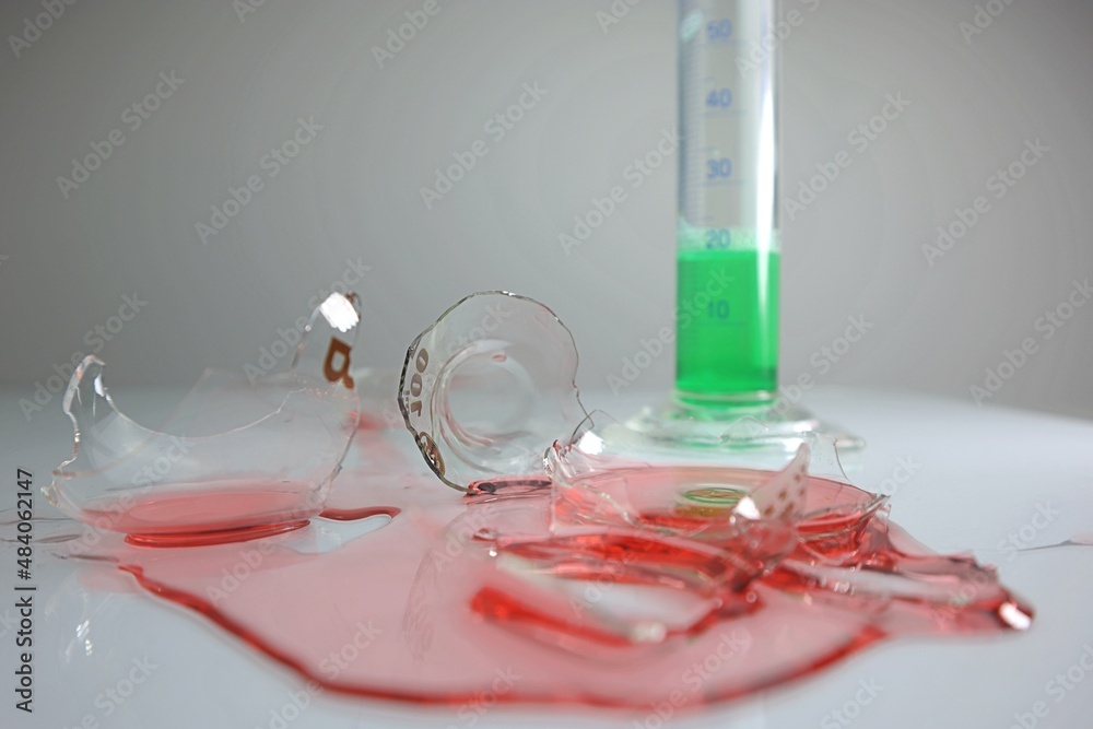 Broken laboratory glass, red liquid chemical spilled from laboratory