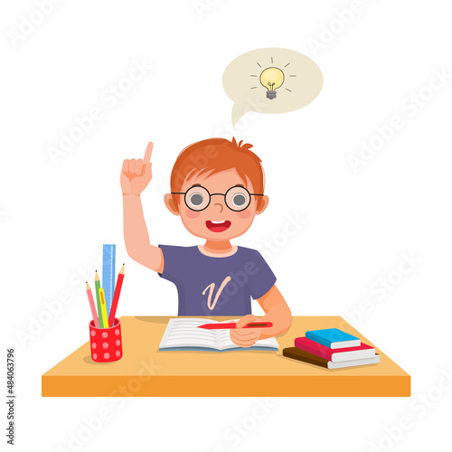 Cute little boy got an idea to solve the problems in math homework raising his index finger pointing up while sitting studying on the desk at home