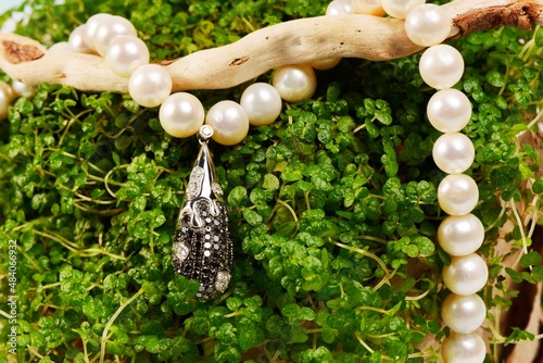 Women's platinum pendant with a black and white diamonds on a preciouse pearls necklace photo