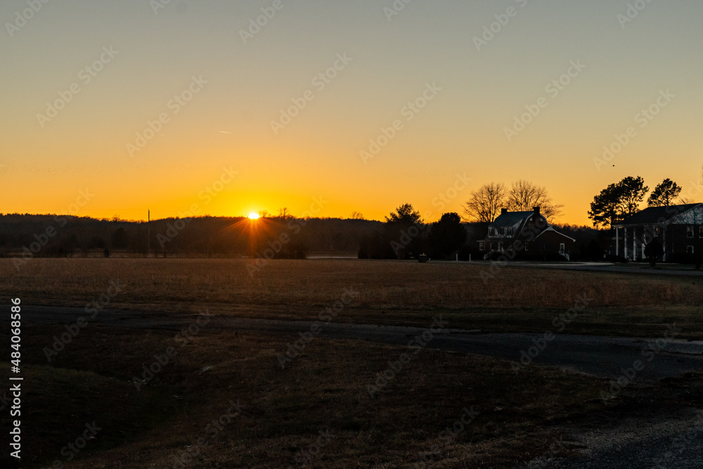 Naklejka premium Sunset over a farm field in a rural neighborhood