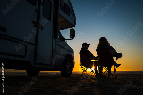 Obraz na płótnie Caucasian Couple Relaxing Next to Their RV Motorhome on a Beach