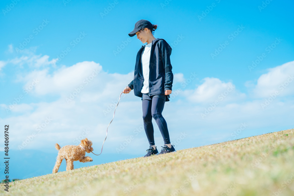 スポーツウェアで犬の散歩をする女性（全身）
