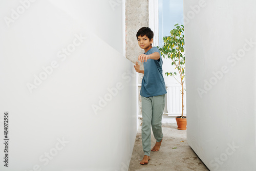 Handsome indian boy walking in a corridor between a wall and a set