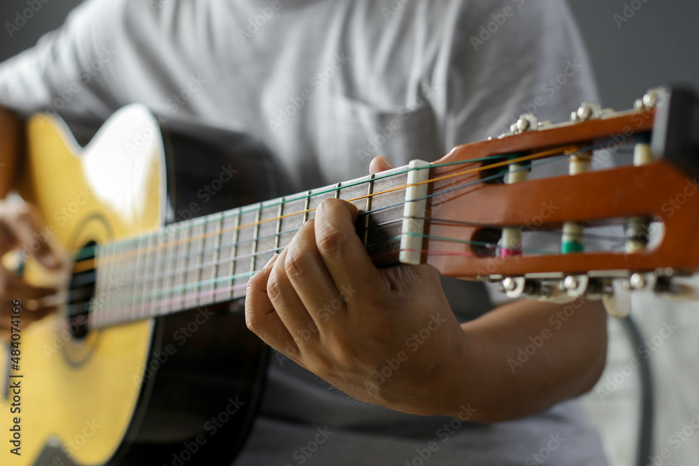 Close-up portrait of hands playing guitar in chord a on blurred background