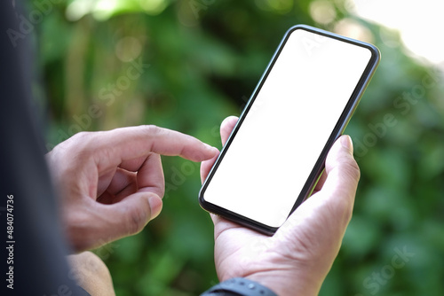 Close up view young man sitting in the park and using smart phone.