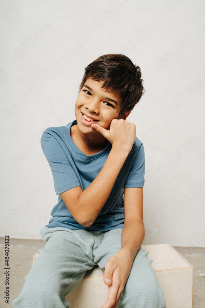Confident indian boy sitting on a wooden box, making a gesture Confident indian boy sitting on a wooden box, making a gesture