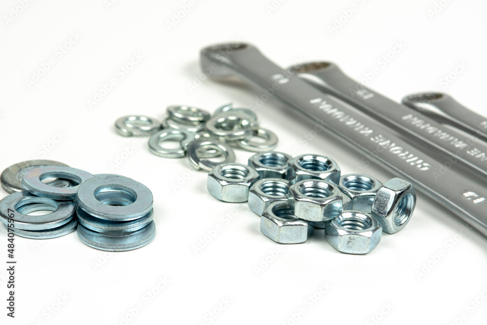 several groups of metal washers and nuts in silver color with wrenches on a white background. close-up several groups of metal washers and nuts in silver color with wrenches on a white background. close-up