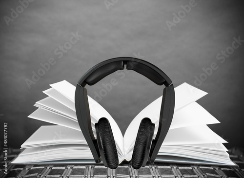 Headphones lying next to old books on the desk. Audiobook Concept