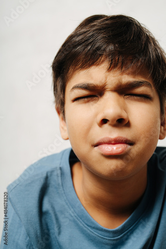 Tense indian boy with closed eyes over white background. close up photo