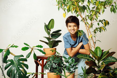 Portrat of an indian boy standing in the middle of a room full of potted plants photo