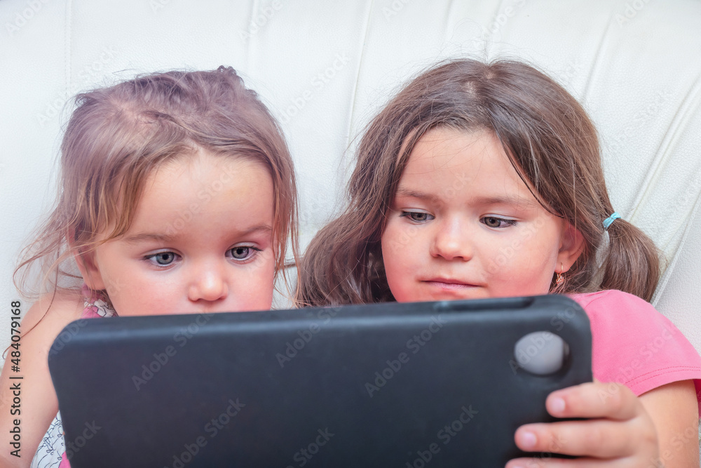 Children enthusiastically watching a tablet together Children enthusiastically watching a tablet together