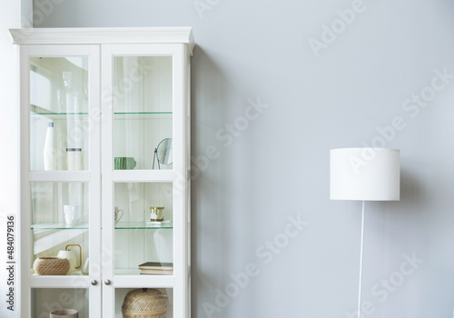 White cabinet and lamp stand near gray wall