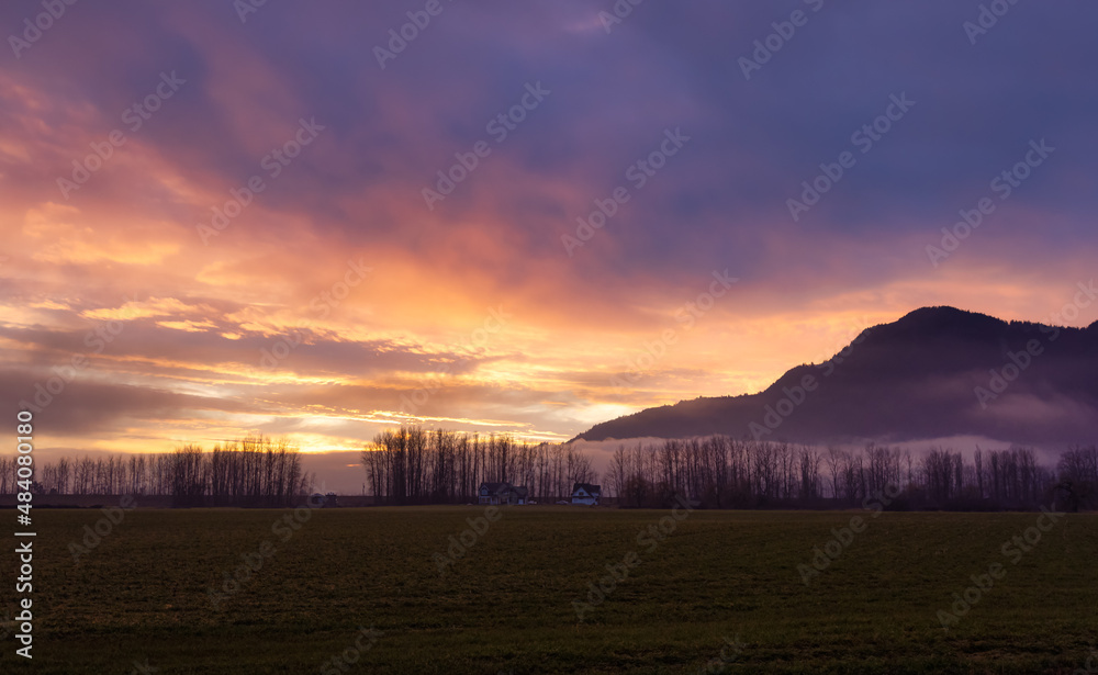 Farm lands and Canadian Mountain Nature Landscape. Dramatic Winter Sunset. Located near Chilliwack and Abbotsford, British Columbia, Canada.