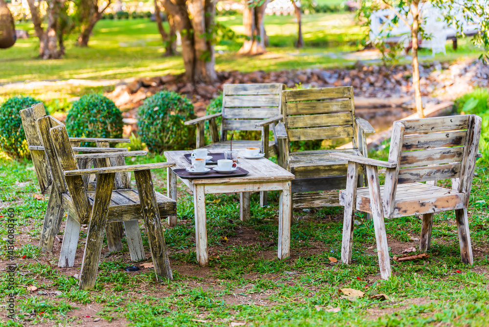 Wooden coffee table and chairs in garden at summer day.