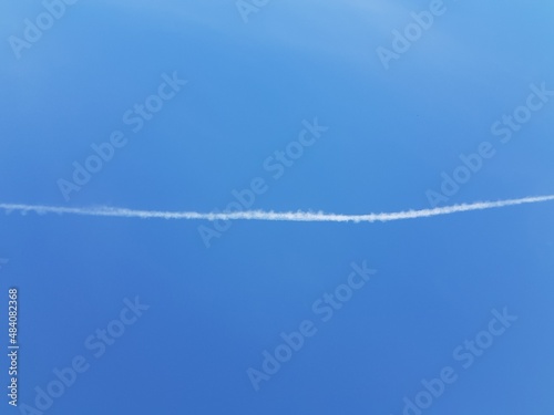 White airplane trail in blue sky