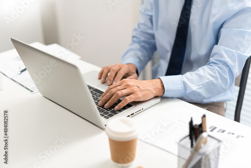 Working Man Conept The man in blue shirt with navy necktie sitting at his desk and typing letters on his notebook