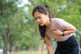 Exhausted female runner suffering painful angina pectoris or asthma breathing problems after training hard on summer.