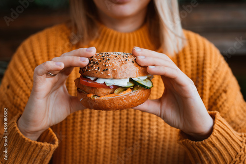 Healthy fast food. Woman holding tasty looking hamburger with vegetables and chicken