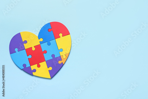 Colorful puzzle pieces in shape of heart on color background. Concept of autistic disorder photo