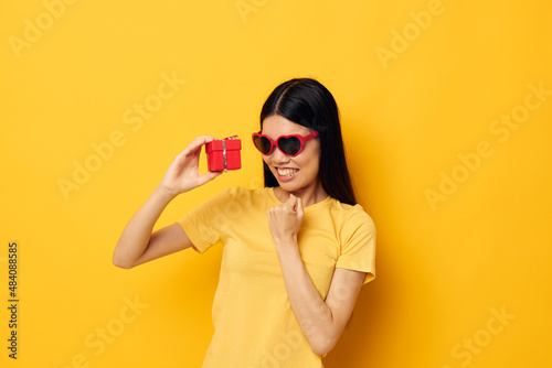 Charming young Asian woman fashion glasses gift holiday yellow background unaltered