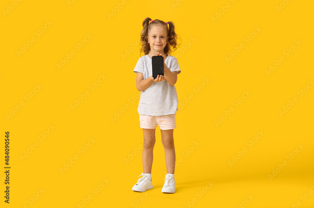Adorable little girl with mobile phone on yellow background Adorable little girl with mobile phone on yellow background