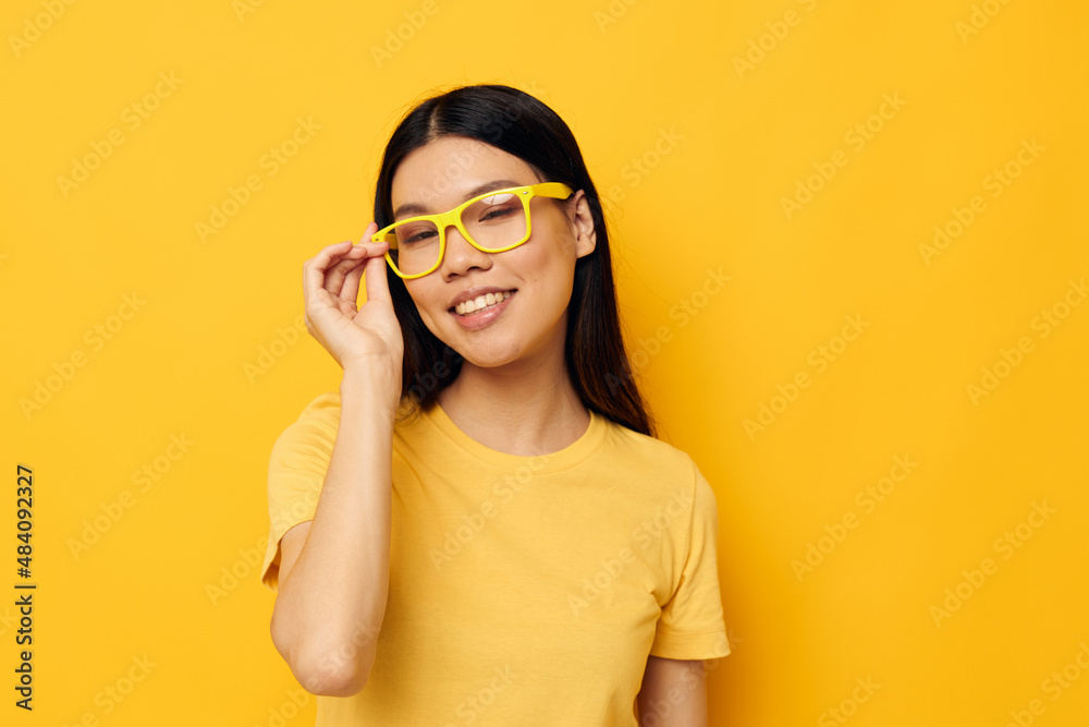 Fototapeta premium pretty brunette in glasses gesturing with hands copy-space yellow background unaltered