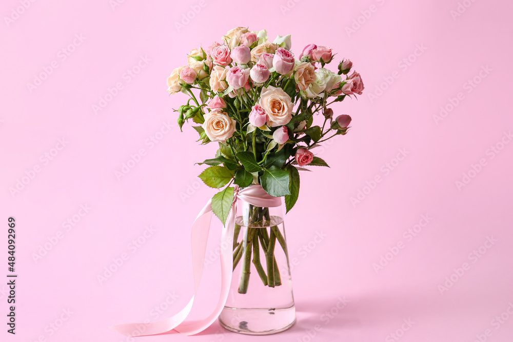 Vase with bouquet of beautiful roses on pink background