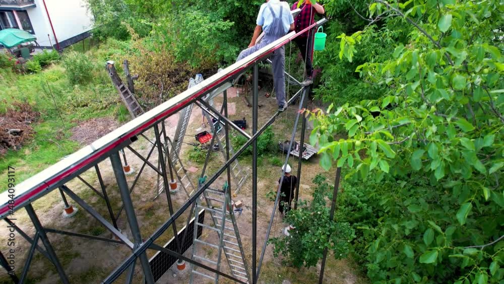 Aerial view of men engineers mounting photovoltaic solar panels to high steel platform. Concept of alternative energy. Aerial view of men engineers mounting photovoltaic solar panels to high steel platform. Concept of alternative energy.