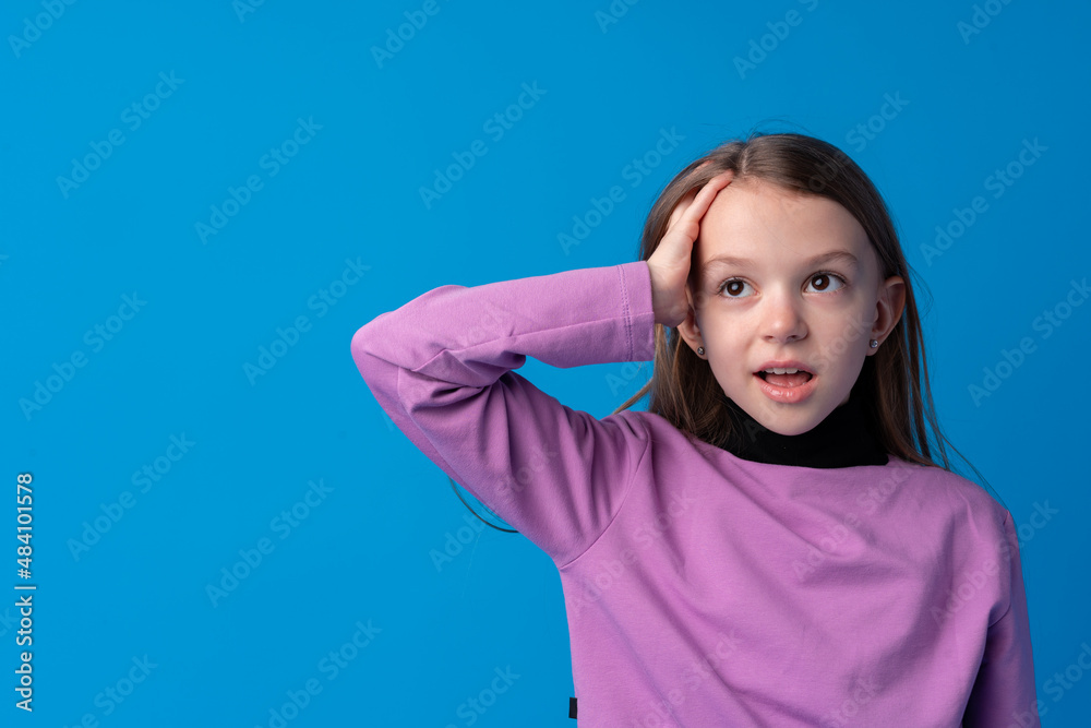 Shocked little girl looking with amazement on blue background Shocked little girl looking with amazement on blue background