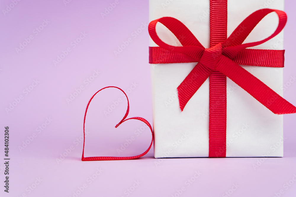 Valentine's Day or birthday concept with copy space. Red ribbon heart and gift box on purple papper Valentine's Day or birthday concept with copy space. Red ribbon heart and gift box on purple papper