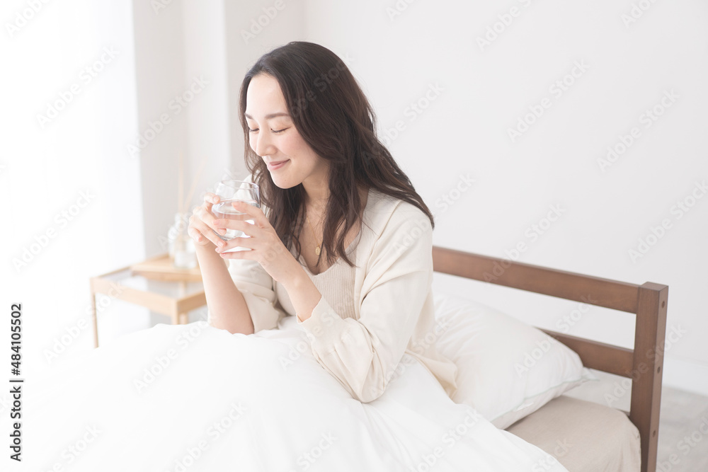 ベッドで水を飲む女性 ベッドで水を飲む女性