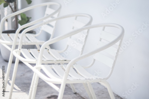 empty white metal chair in line with white wall 