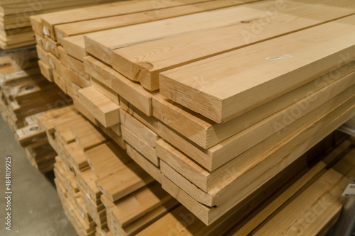 A stack of boards in a hardware store. Wooden products for construction and repair. Assortment of wooden sticks. Construction materials in warehouse. Selective focus
