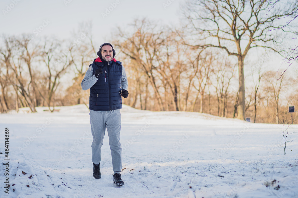 Adult man is exercising in park in wintertime. He is jogging. Adult man is exercising in park in wintertime. He is jogging.