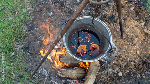 Mulled wine in a tourist pot over hot camp fire. Mulled wine by the fire. Mulled wine cooked on fire outdoors. Picnic.