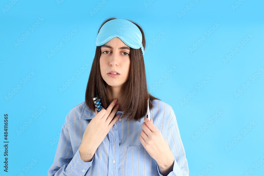 Attractive sick woman in sleep mask on blue background Attractive sick woman in sleep mask on blue background