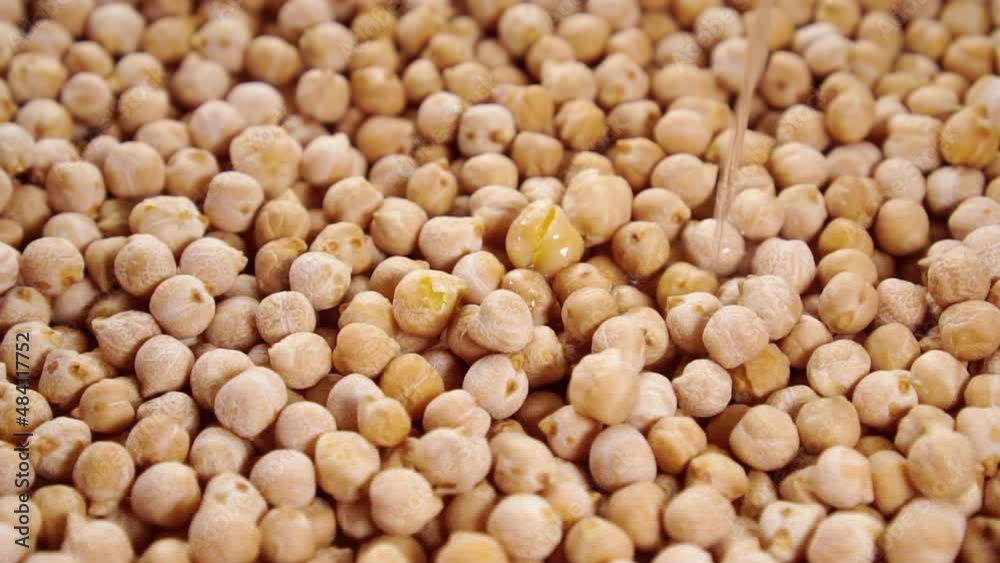 Pouring water into a bowl with dry chickpeas in slow motion. Close-up. Washing and soaking dry uncooked dry garbanzo beans. Cooking traditional food. Rotation Pouring water into a bowl with dry chickpeas in slow motion. Close-up. Washing and soaking dry uncooked dry garbanzo beans. Cooking traditional food. Rotation
