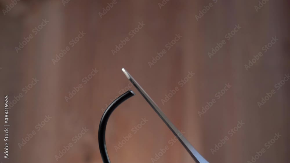 Scissors cutting black USB cable close up. On brown background. Internet restrictions concept. Network interruption idea Scissors cutting black USB cable close up. On brown background. Internet restrictions concept. Network interruption idea
