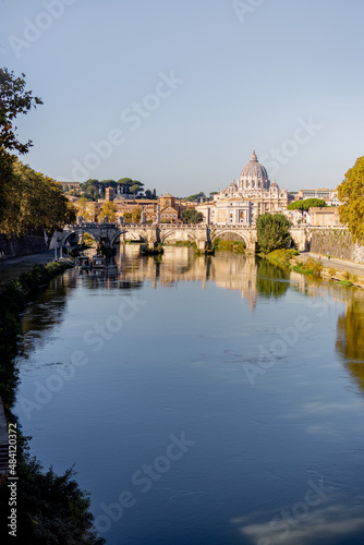 Landscape of Tiber river and green surroundings at sunny morning in Rome. Dome of famous saint Peter basalica on the skyline. Traveling Italy photo