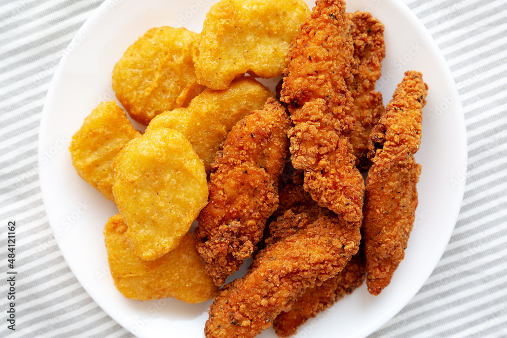 Homemade Nuggets and Chicken Tenders on a Plate, top view. Overhead, from above, flat lay. Homemade Nuggets and Chicken Tenders on a Plate, top view. Overhead, from above, flat lay.