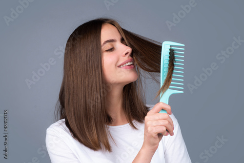 Attractive woman combing hair. Beautiful girl combs hair. Haircare concept.