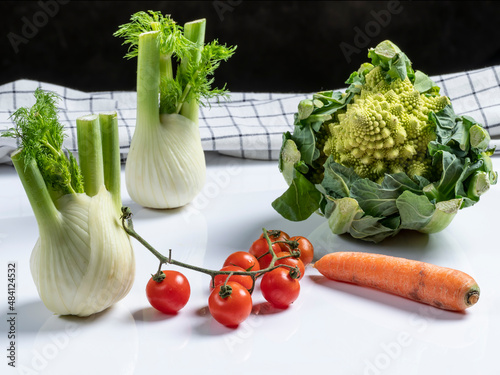 Composition of fresh vegetables with Roman cabbage, carrot, cherry tomatoes and fennel