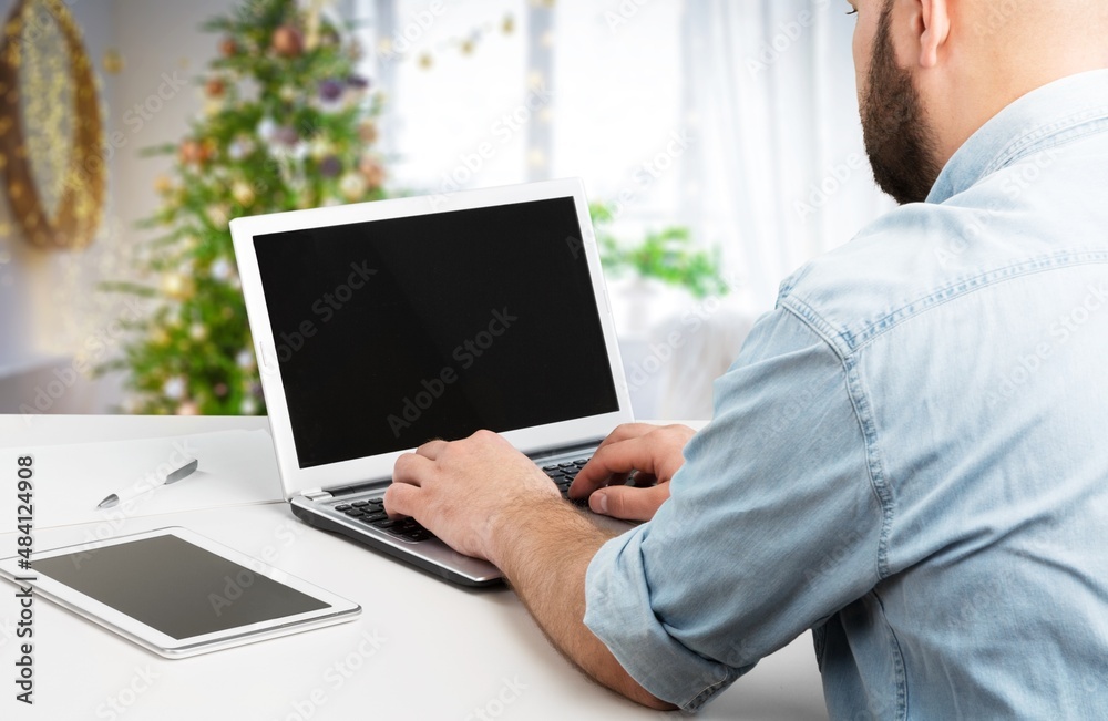 Person work on laptop computer with a blank display screen. home interior decorated for Christmas