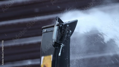 snow removal in winter after a heavy snowstorm. Snowfall and storm. Clearing the road from snow on a frosty day. The snowplow throws flakes of snow on the street. Slow-motion close-up