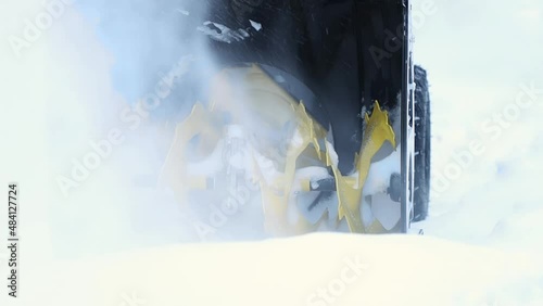 On a winter day, in the yard after a heavy snowfall, clean the path in front of the house from snow drifts with a snowplow, rake and throw the snow powder aside through the pipe. Slow motion