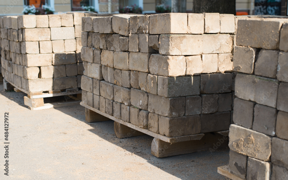 Old dirty concrete large blocks, used curbs on pallets outdoors. Construction material Old dirty concrete large blocks, used curbs on pallets outdoors. Construction material