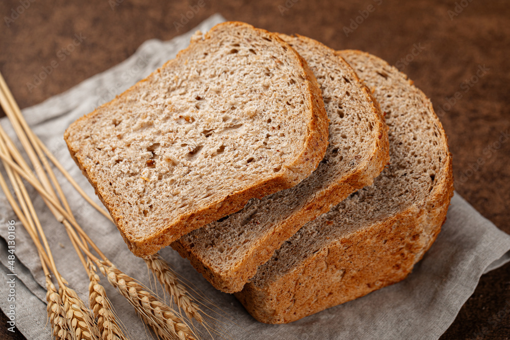 Fresh baked sliced loaf of rye bread on a brown background