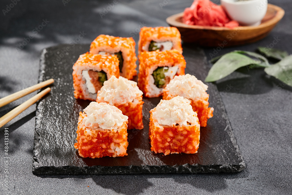 Maki sushi on dark stone table. California maki with tobiko. Sushi roll